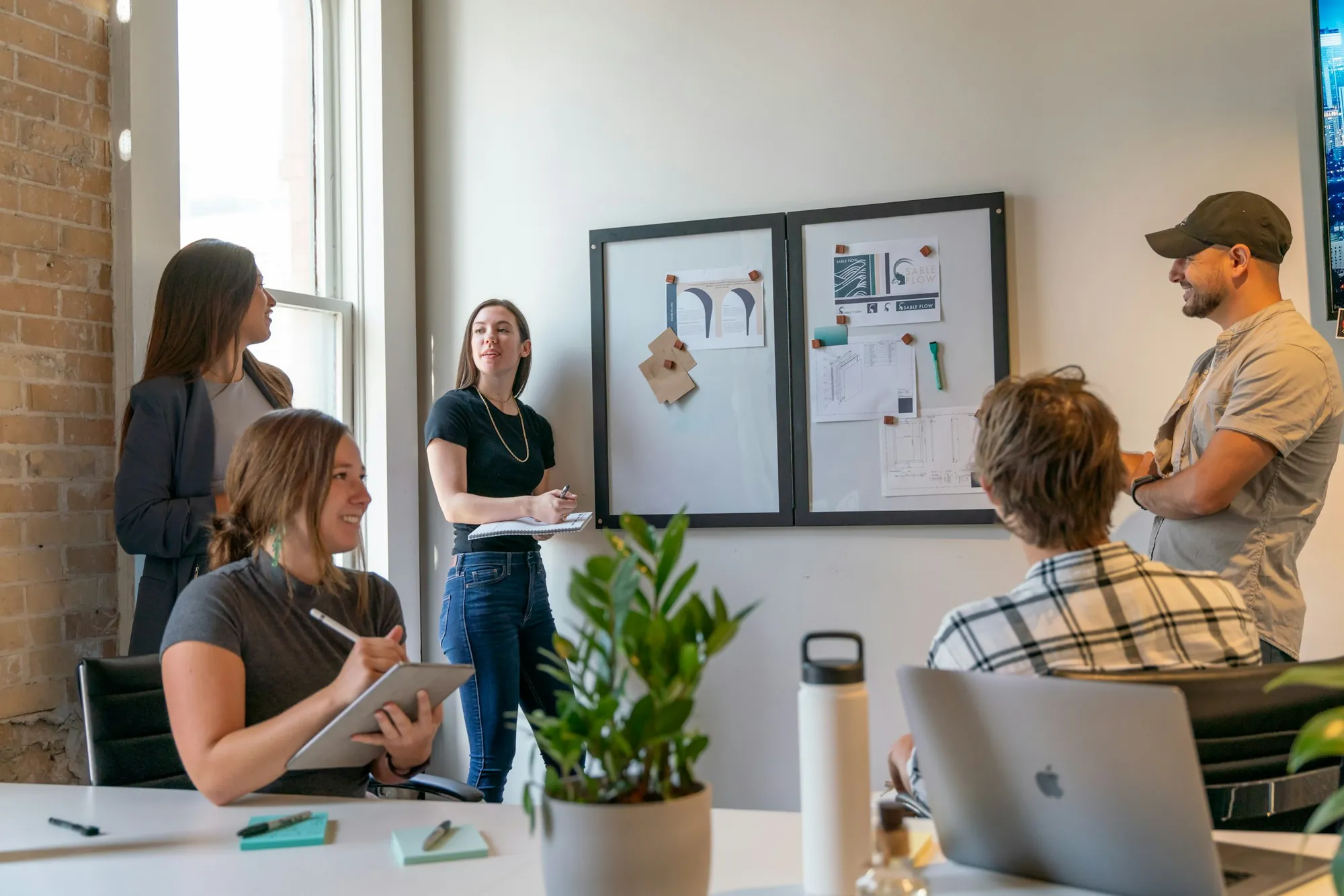 Team discussing ideas in front of a pin board in a sunny office