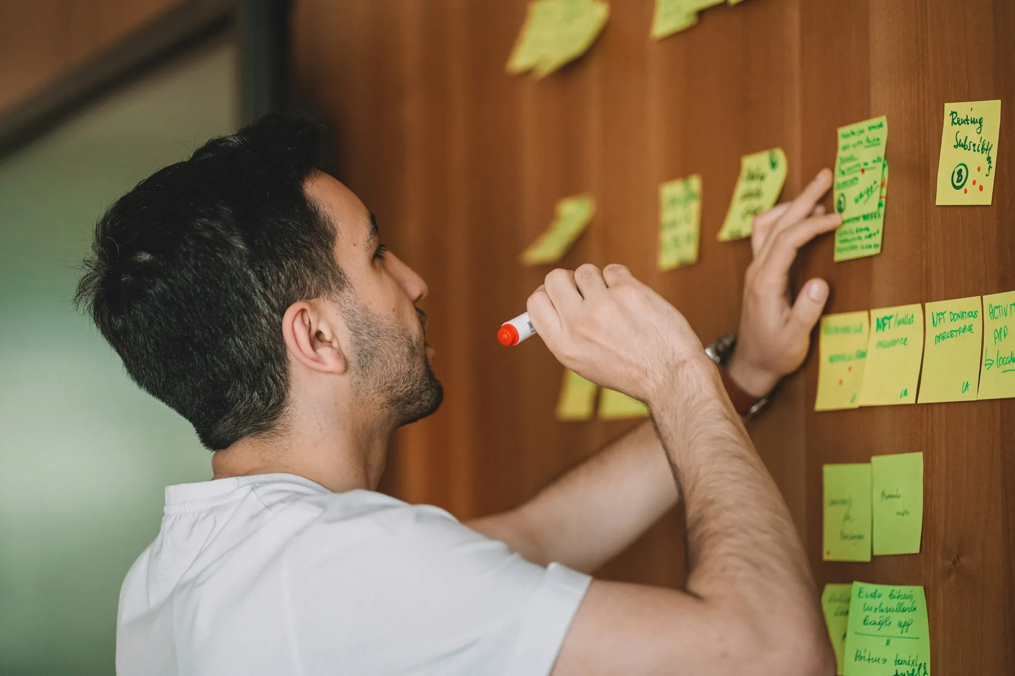 Man writing on sticky notes on a planning wall