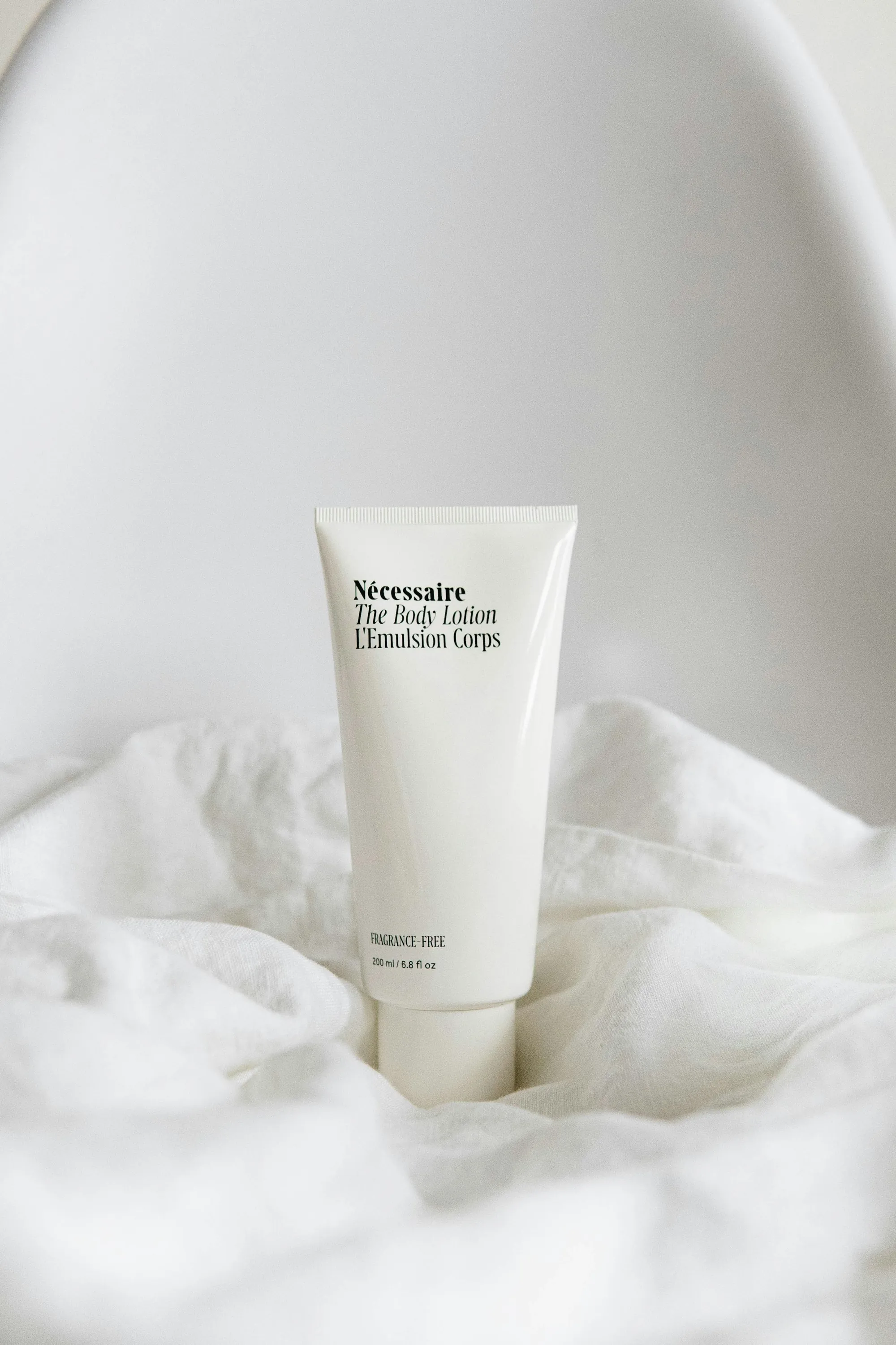 White skincare tube resting on soft white fabric